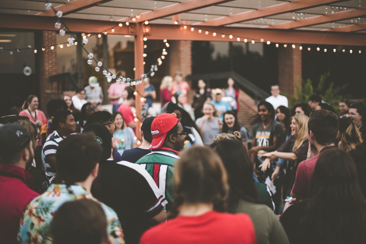 Large outdoor crowd gathering at an event with string lights