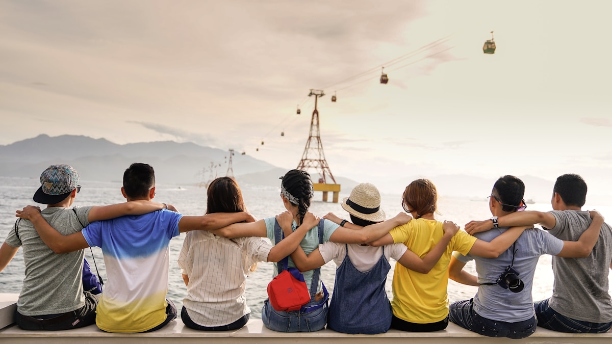 Group of friends sitting together with arms around each other overlooking water
