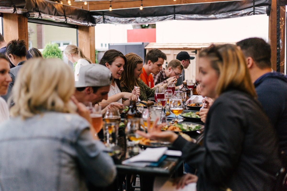 Group of people having dinner and drinks at a long outdoor table